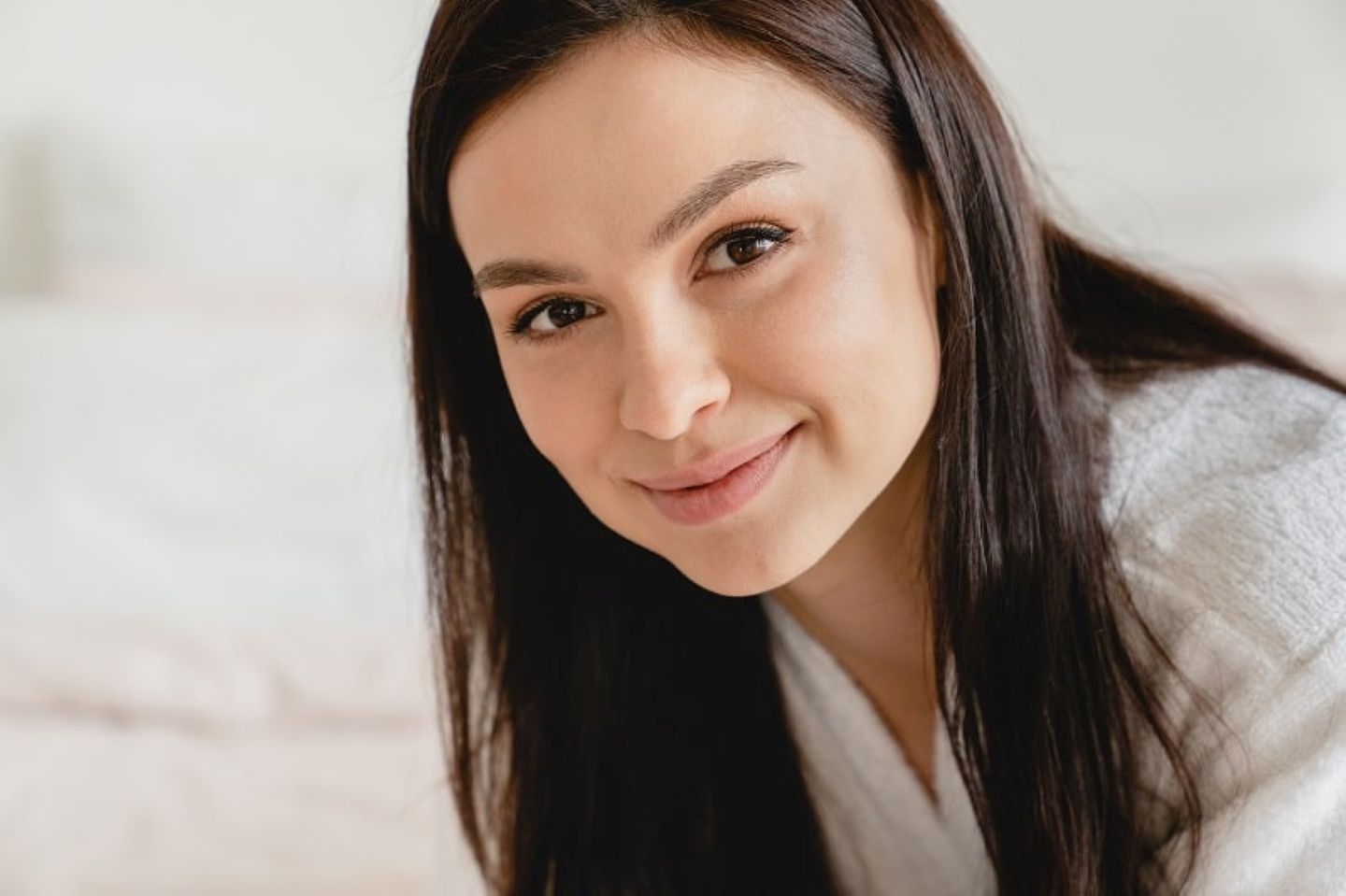 Smiling woman with natural, clear skin looking at the camera indoors