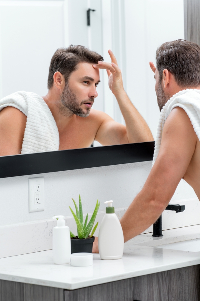 Man looking in the mirror inspecting wrinkles and skin texture