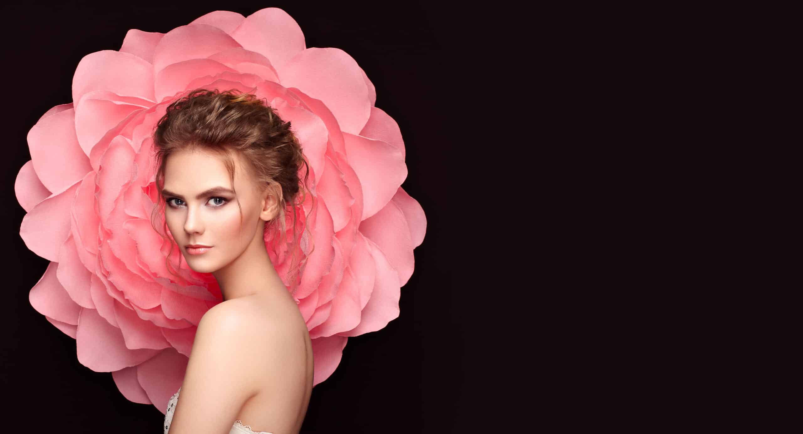 Woman posing in front of large pink flower backdrop