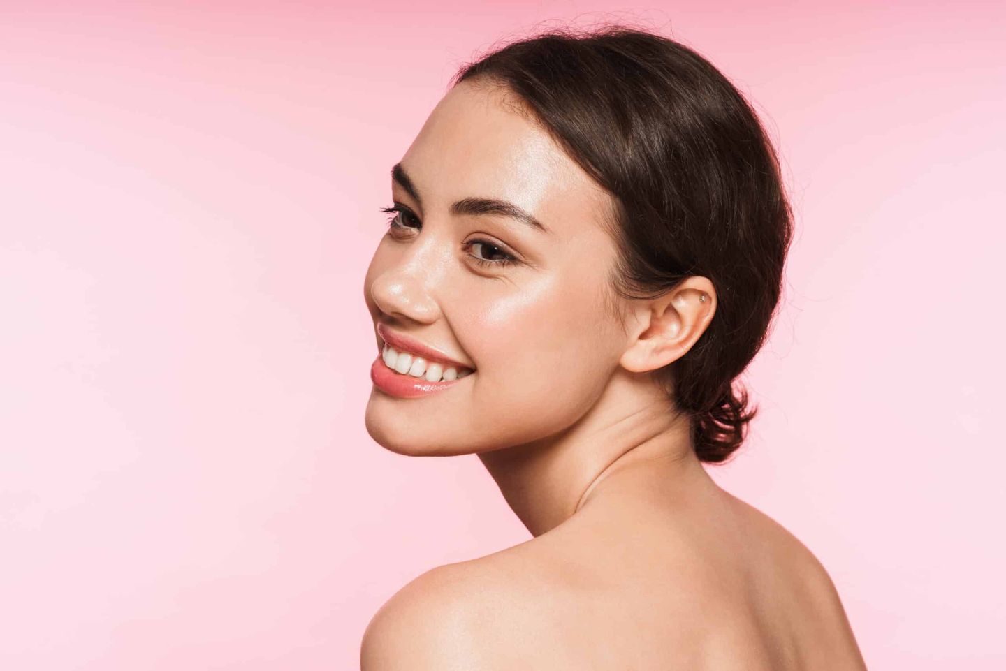 Smiling woman with glowing skin on a pink background